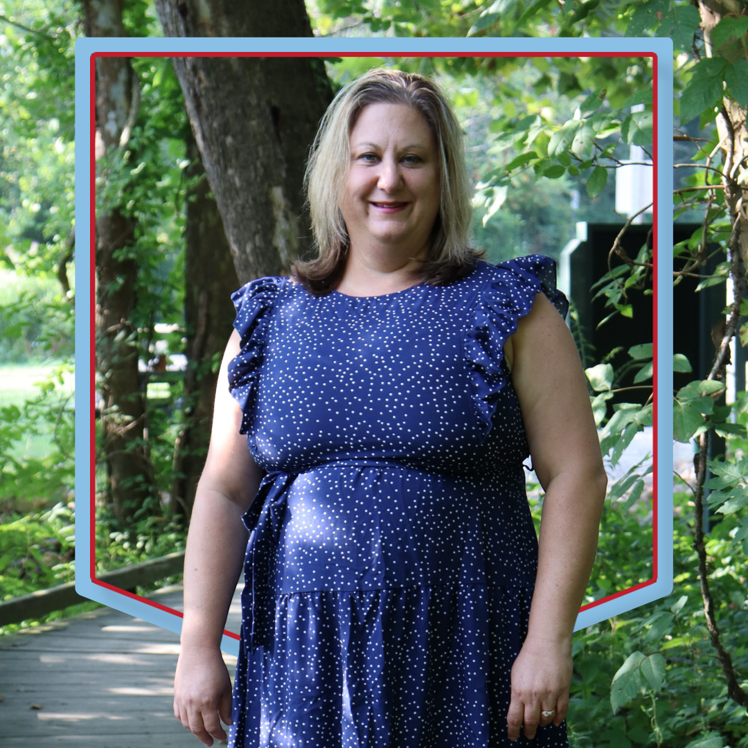 Kim Kabrich poses in front of a wooded background.